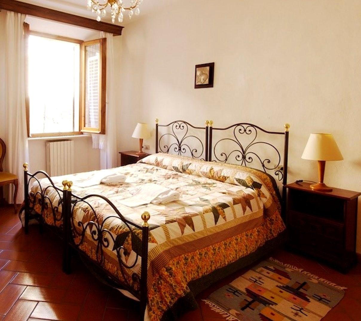 Camera matrimoniale con letto in ferro battuto e copriletto patchwork