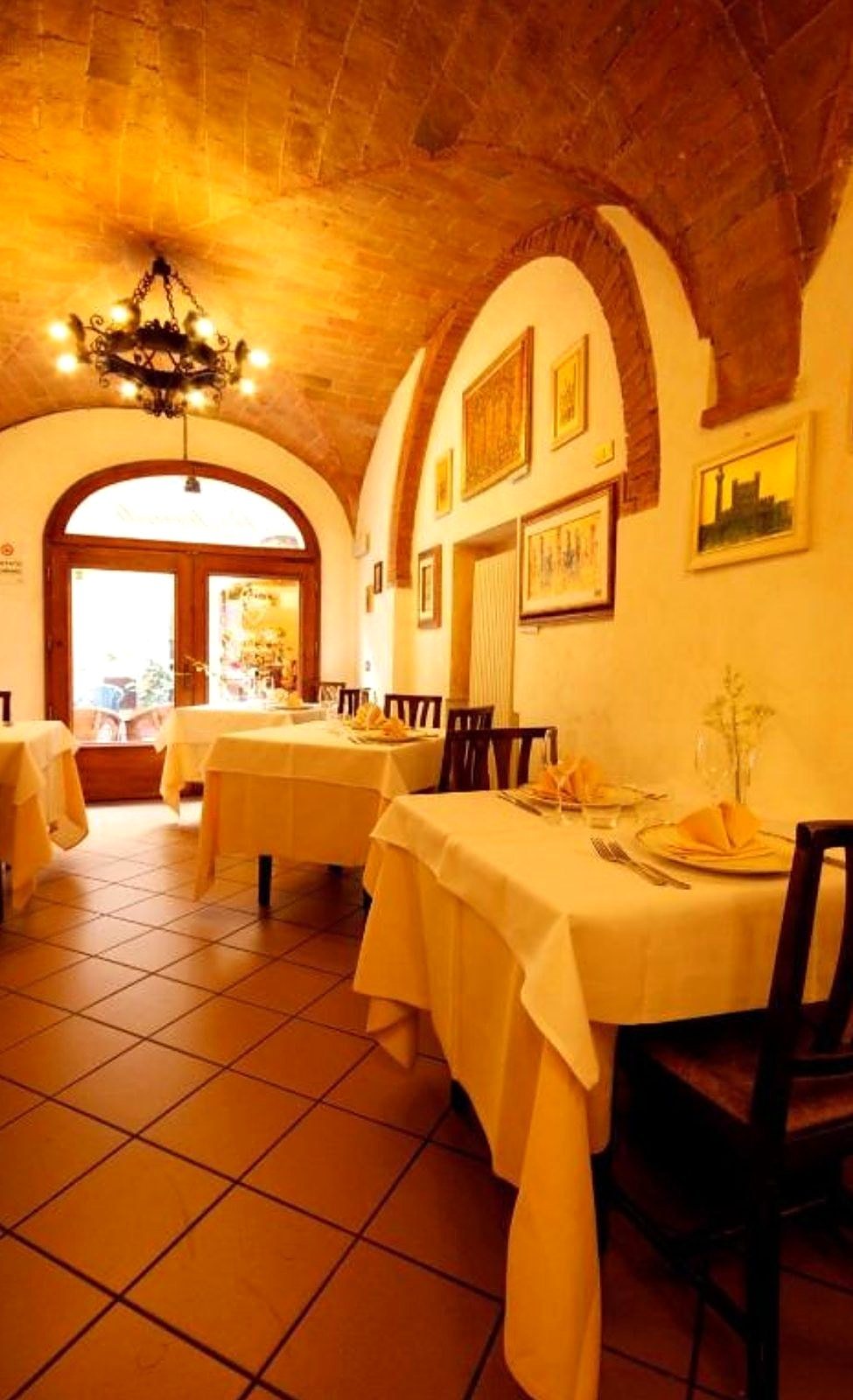 La sala del ristorante con tovaglie gialle e pavimento in cotto