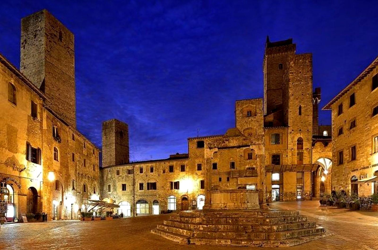 Piazza della Cisterna di sera con le torri illuminate