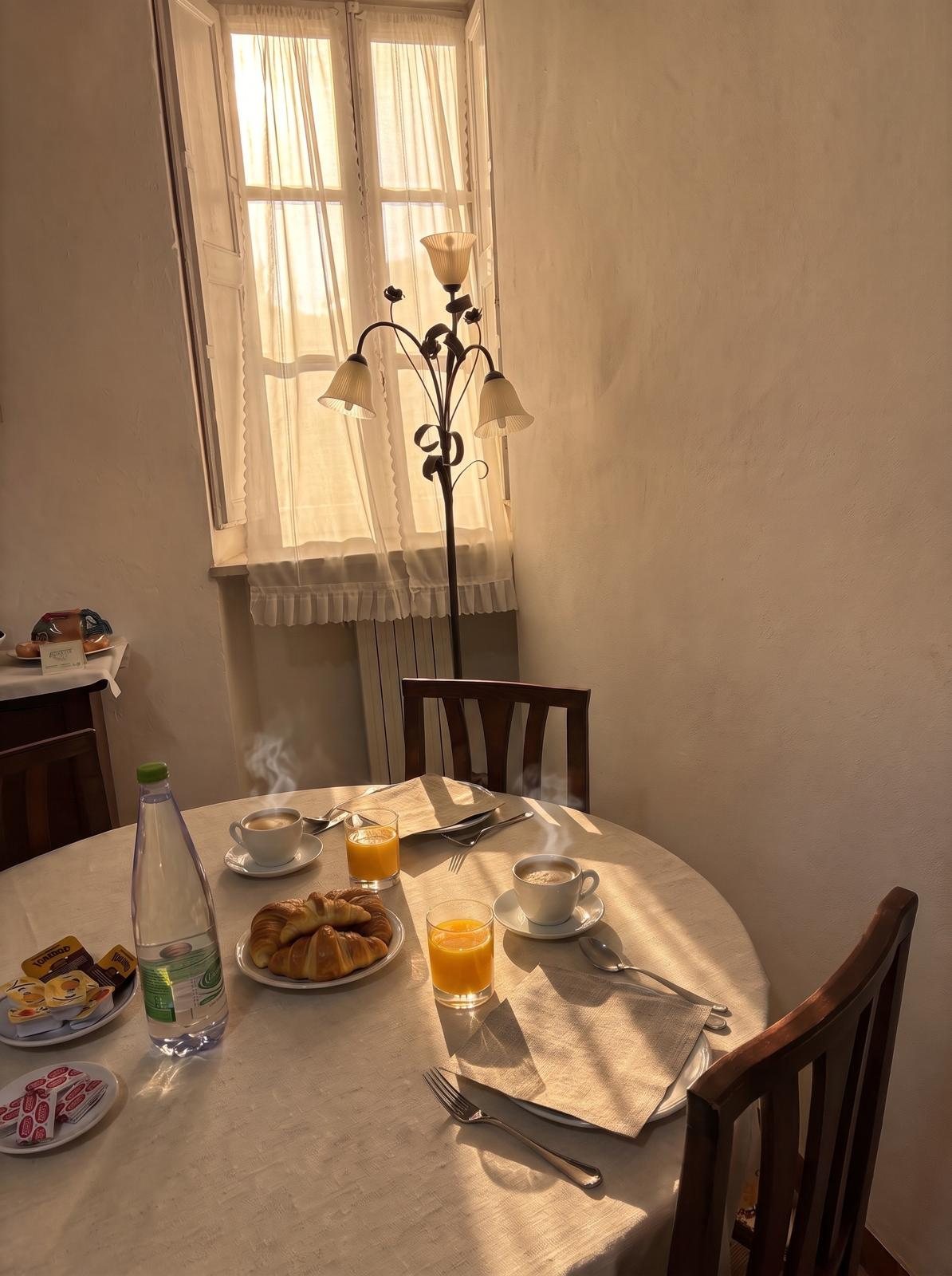 Colazione con caffè, spremuta e cornetti al sole del mattino